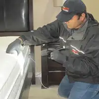Bed bug inspection technician checking a mattress and bed frame for signs of infestation in Worcester, MA
