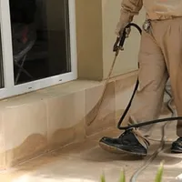 General pest control technician spraying exterior perimeter around a home in Worcester, MA