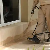 General pest control technician spraying exterior perimeter around a home in Worcester, MA