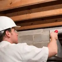 Termite inspection technician checking a basement wall and framing for termite activity in Worcester, MA